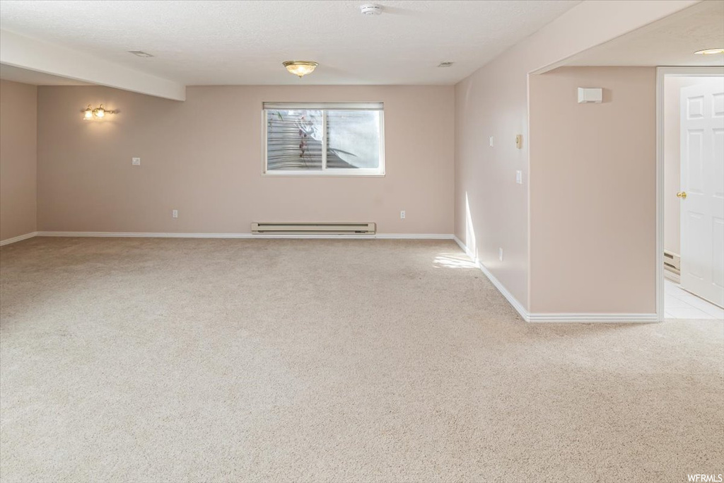Empty room featuring light carpet and baseboard heating