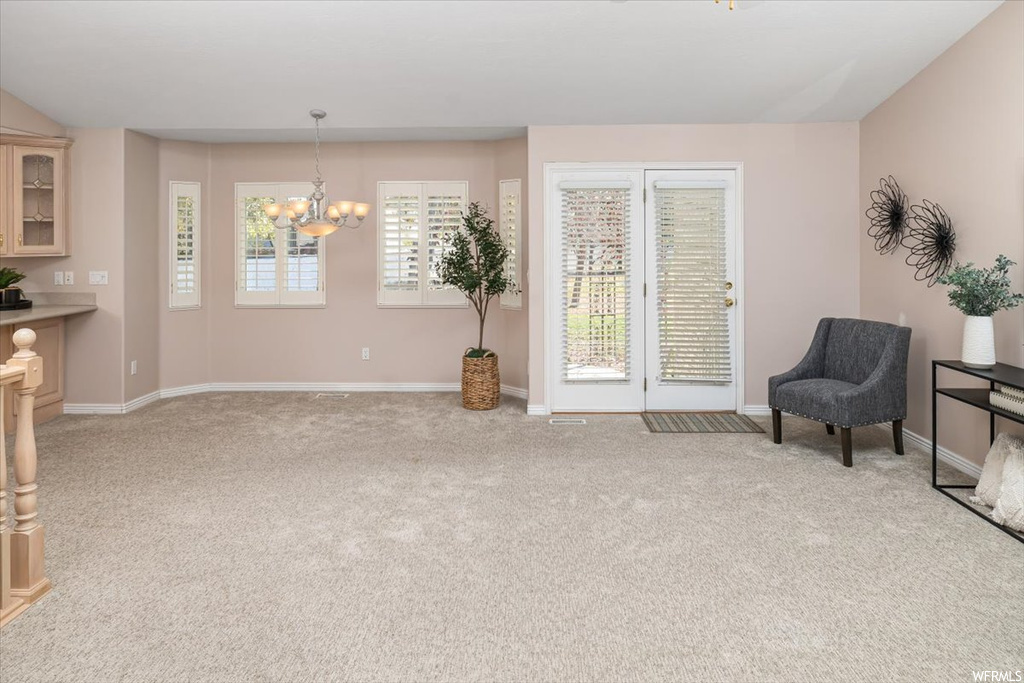 Living area with light colored carpet and a chandelier