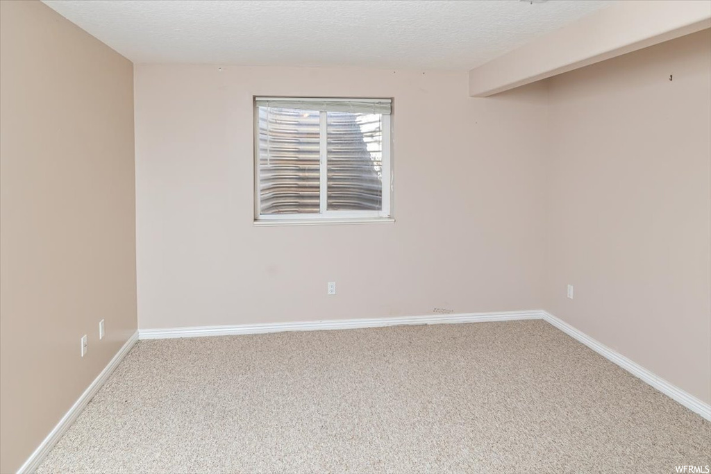 Empty room featuring a textured ceiling and light carpet