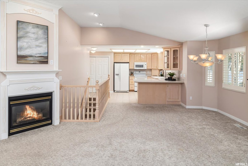 Kitchen with light brown cabinets, white appliances, and light colored carpet