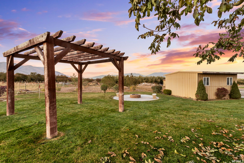 Yard at dusk featuring a mountain view and a pergola