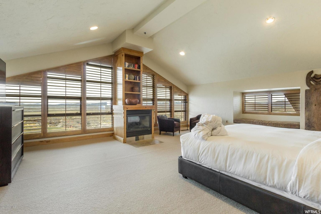 Bedroom featuring light colored carpet, a fireplace, and vaulted ceiling