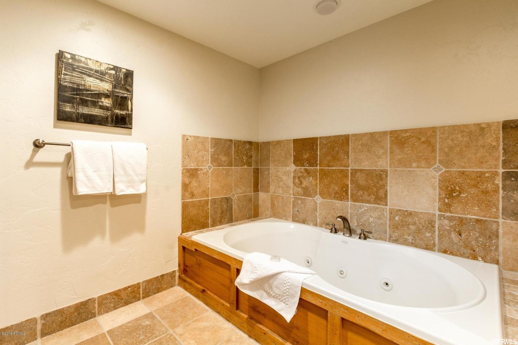 Bathroom featuring tile floors, a washtub, and tile walls