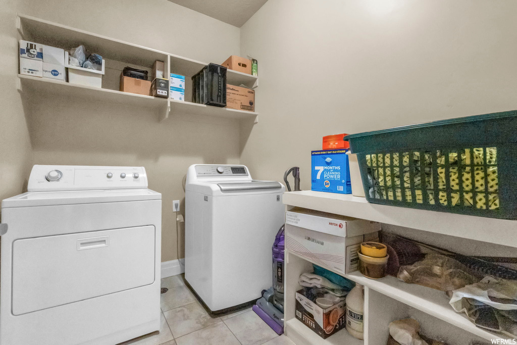 Laundry area featuring washing machine and clothes dryer and light tile floors