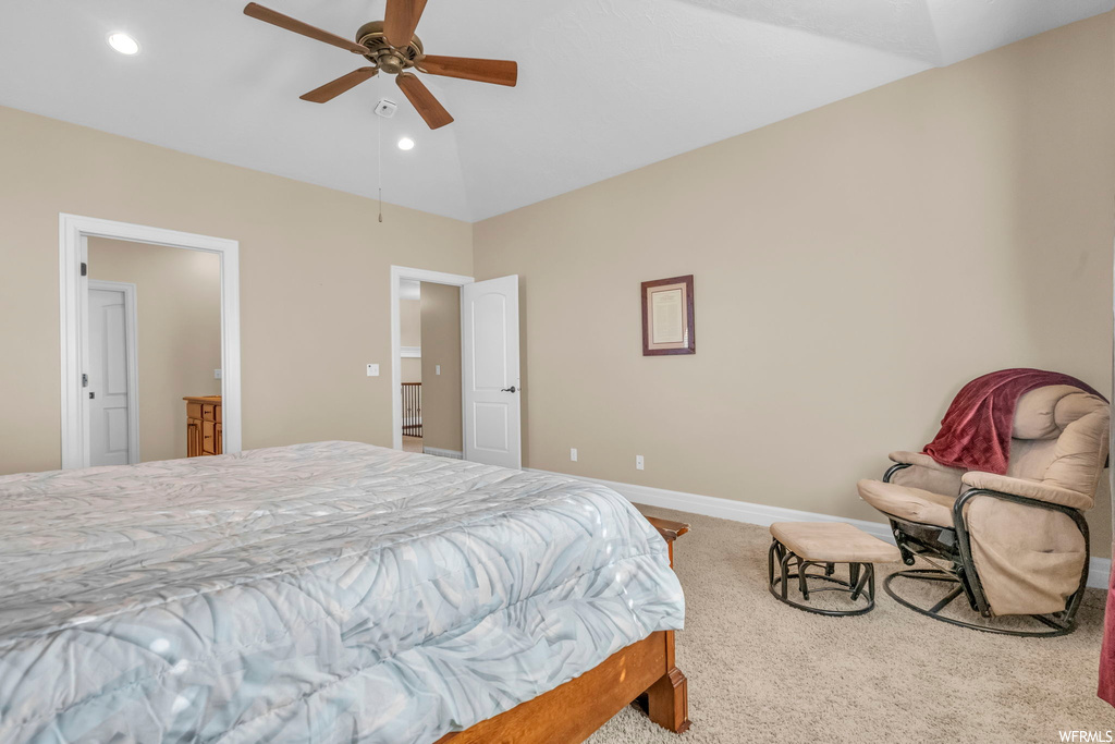 Bedroom featuring vaulted ceiling, ceiling fan, ensuite bath, and light colored carpet