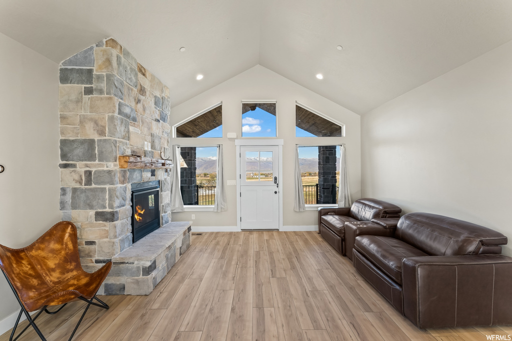 Living room featuring light hardwood / wood-style floors, a fireplace, and high vaulted ceiling