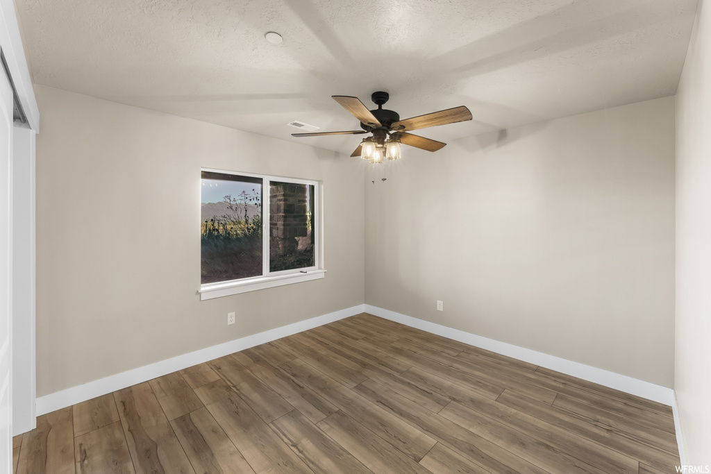 Empty room with ceiling fan and hardwood / wood-style flooring