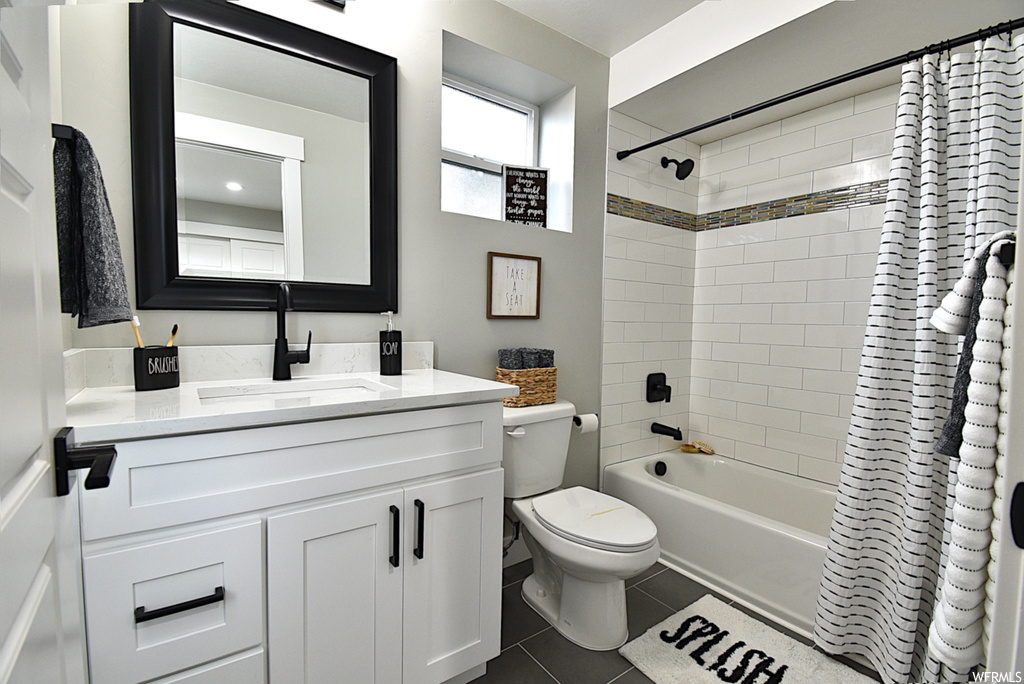 Full bathroom featuring tile floors, vanity, toilet, and shower / bath combo with shower curtain