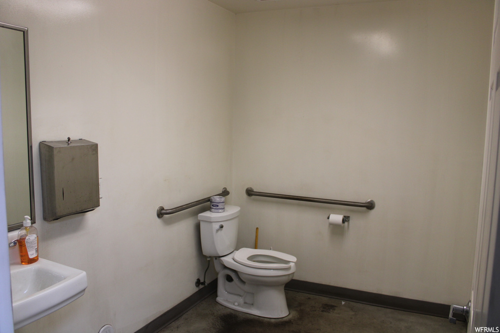 Bathroom featuring concrete floors, toilet, and sink