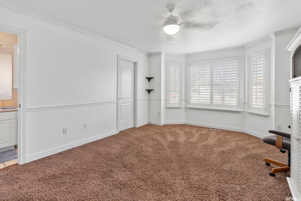 Unfurnished bedroom with connected bathroom, ceiling fan, light carpet, and ornamental molding