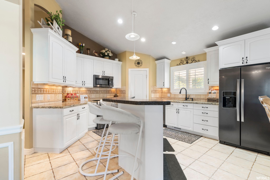 Kitchen with backsplash, stainless steel appliances, white cabinets, and a kitchen island