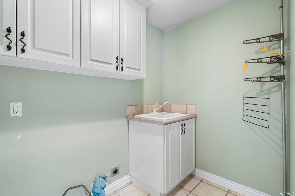 Laundry room with sink, cabinets, light tile floors, and hookup for an electric dryer