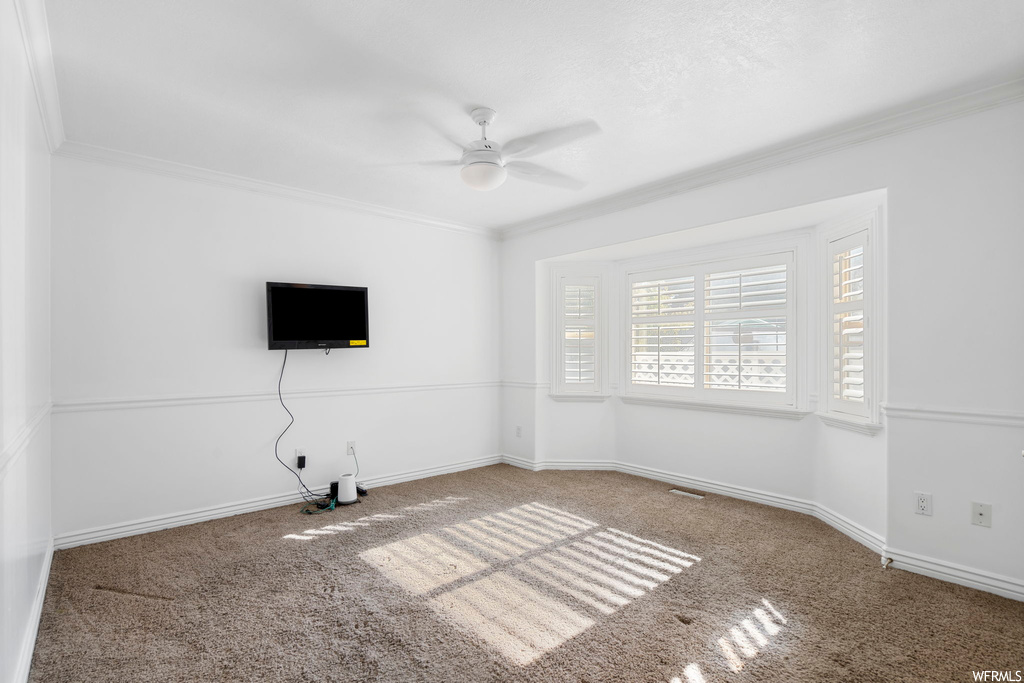 Unfurnished room with light carpet, crown molding, and ceiling fan