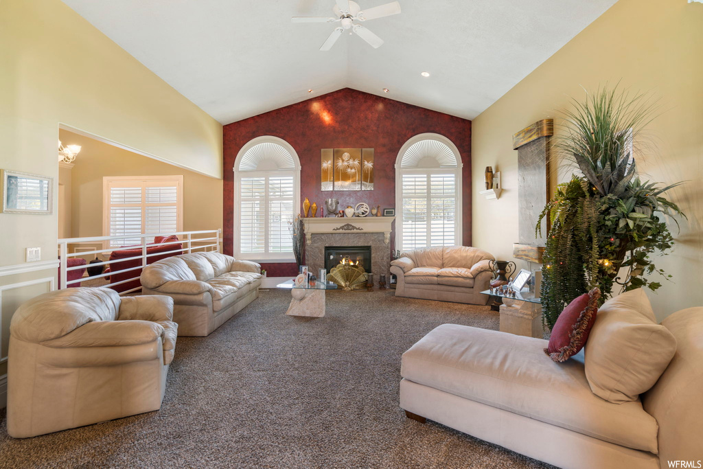 Living room featuring carpet, a fireplace, vaulted ceiling, and ceiling fan