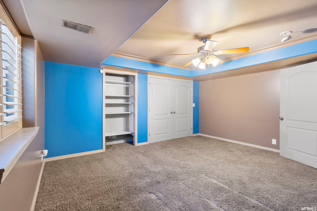 Unfurnished bedroom with a closet, carpet floors, ceiling fan, and ornamental molding