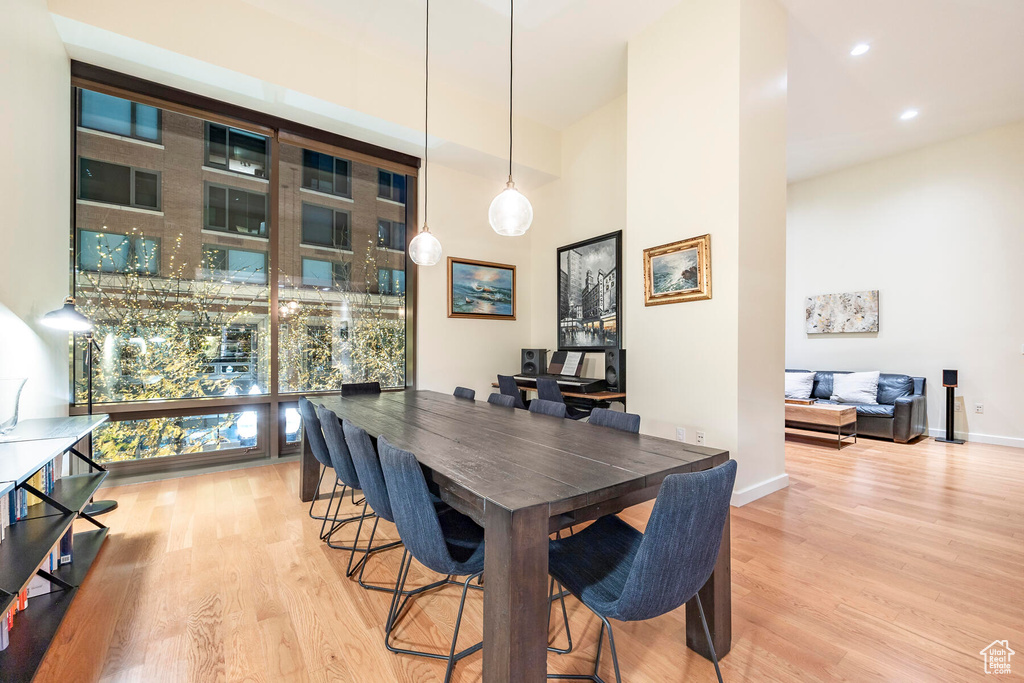 Dining space featuring expansive windows, light hardwood / wood-style flooring, and a high ceiling