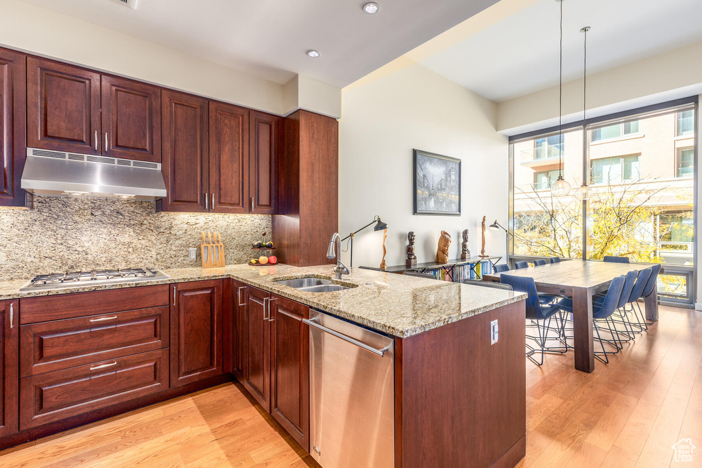 Kitchen featuring sink, appliances with stainless steel finishes, decorative light fixtures, and light wood-type flooring