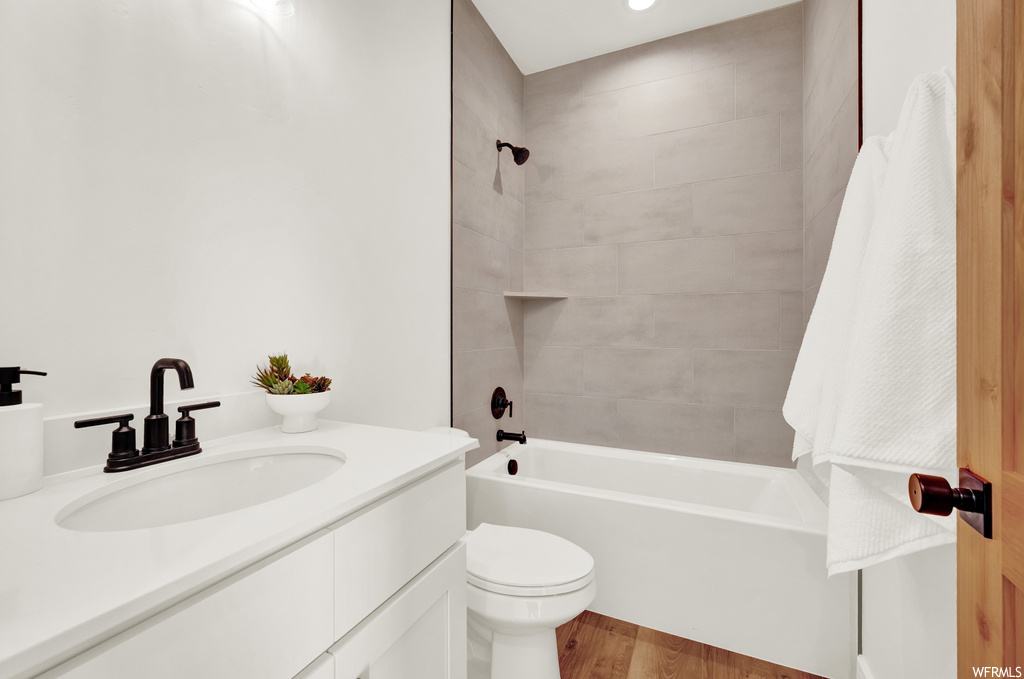 Full bathroom featuring vanity, toilet, hardwood / wood-style flooring, and tiled shower / bath