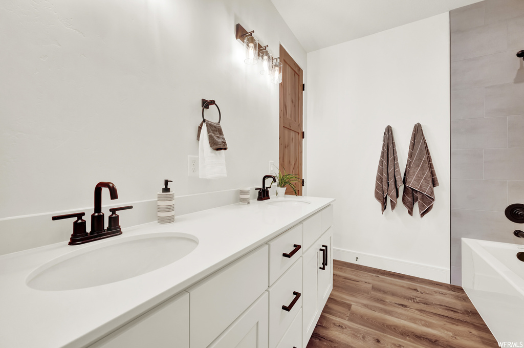 Bathroom featuring double vanity, hardwood / wood-style floors, and tiled shower / bath