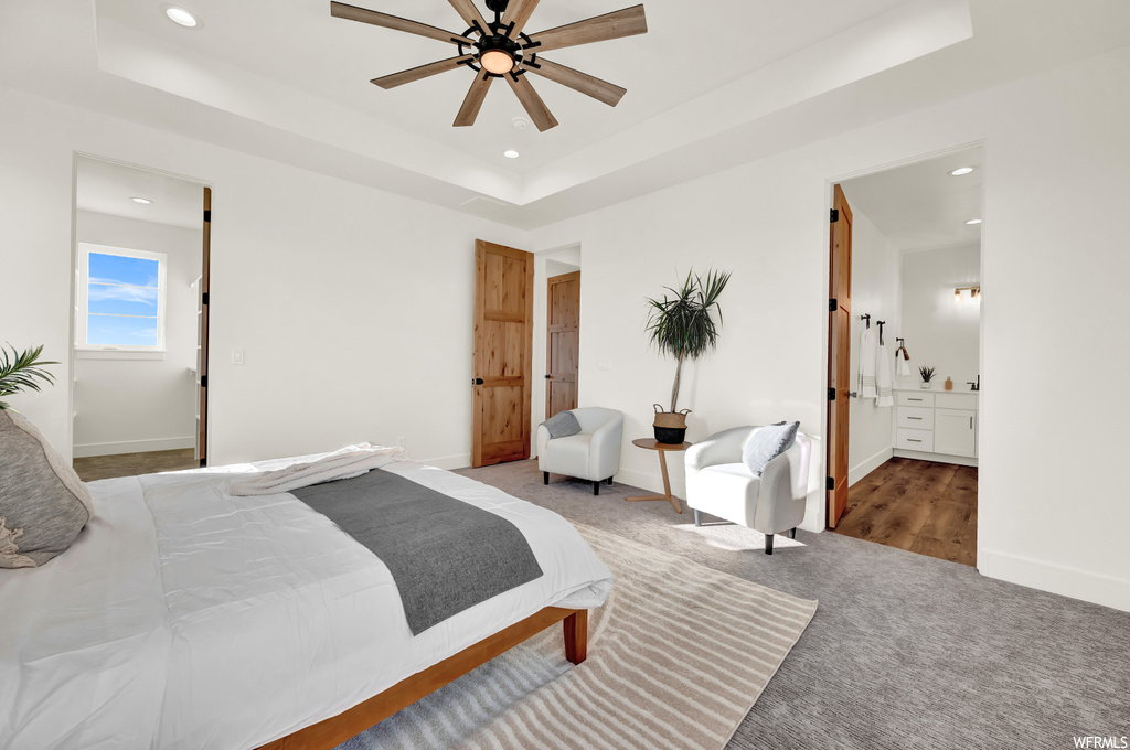 Carpeted bedroom with ceiling fan, a raised ceiling, and ensuite bath