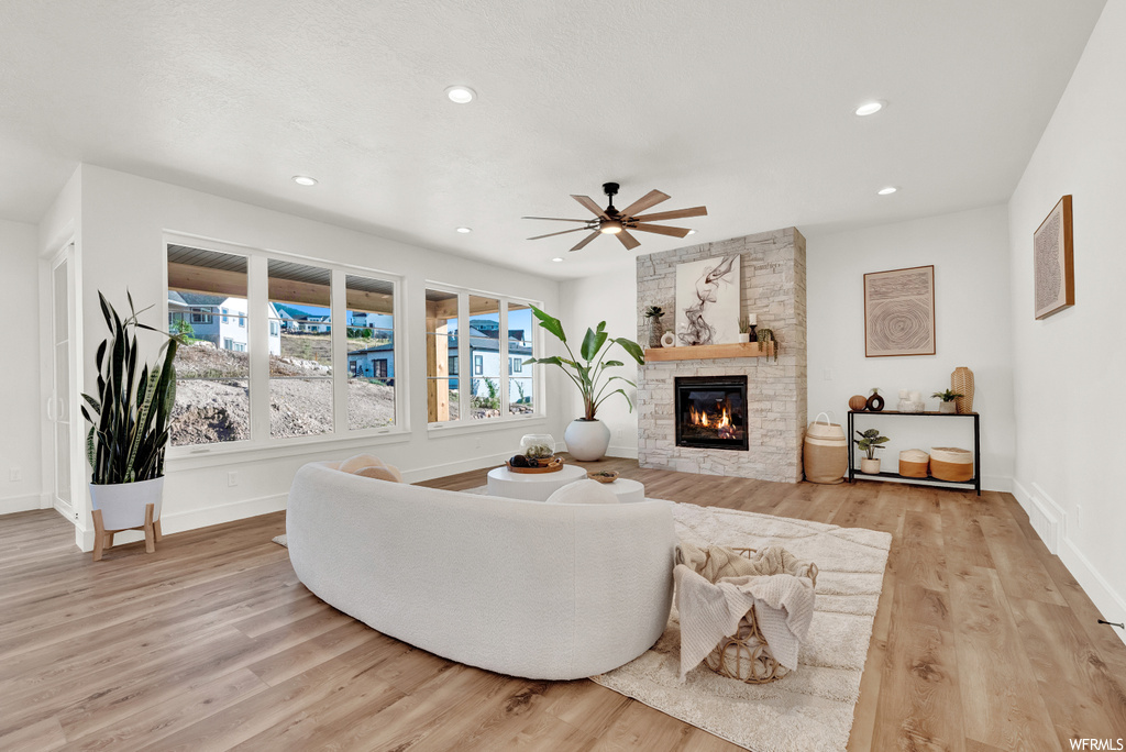 Living room featuring a fireplace, ceiling fan, and light hardwood / wood-style flooring