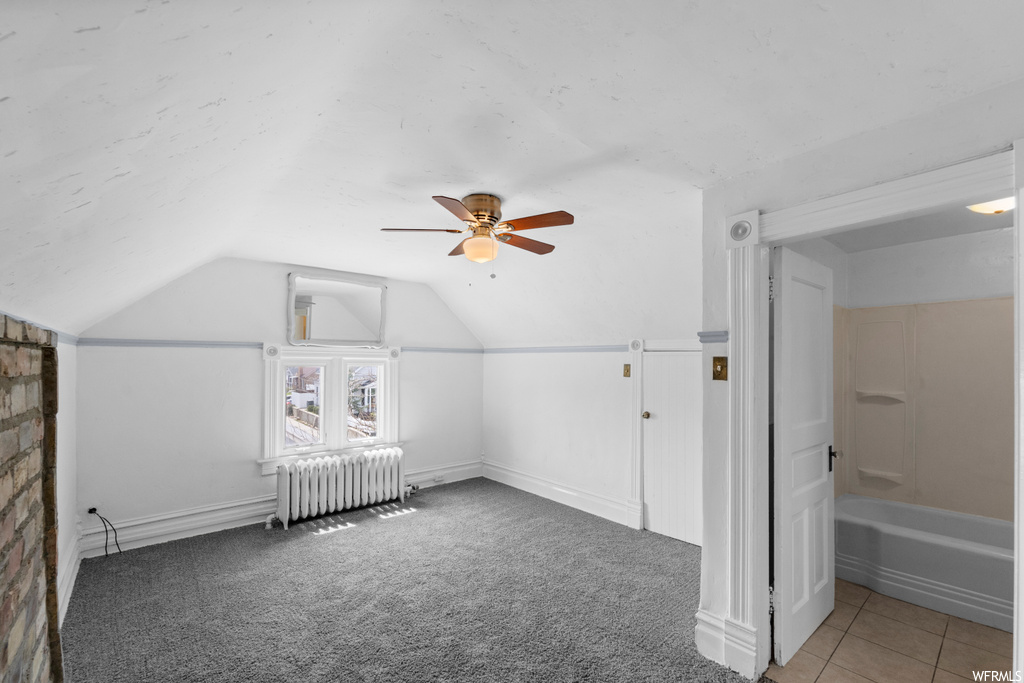 Bonus room featuring light colored carpet, vaulted ceiling, radiator heating unit, and ceiling fan