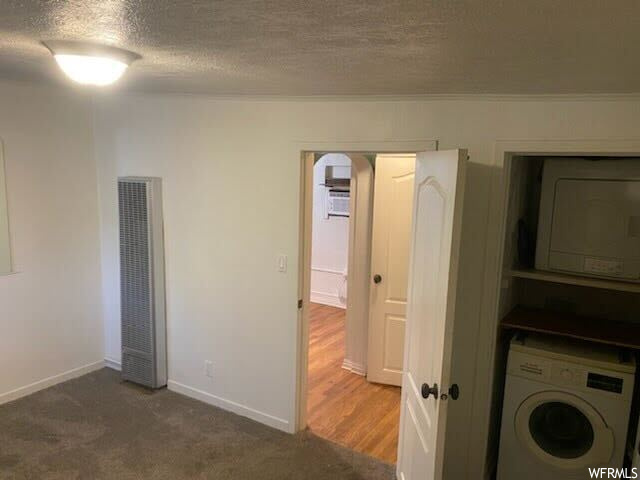 Laundry room featuring washer / clothes dryer, dark colored carpet, and a textured ceiling