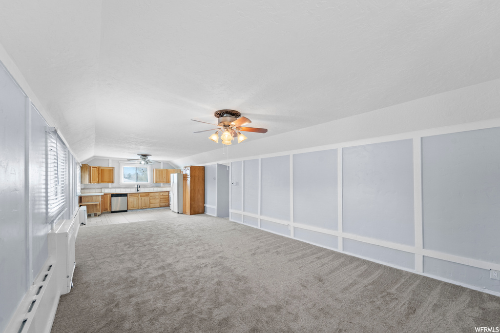 Interior space with light colored carpet, sink, white refrigerator, and ceiling fan