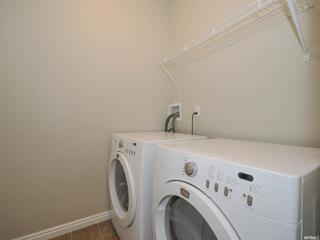 Clothes washing area with washer hookup, washer and clothes dryer, and dark tile floors