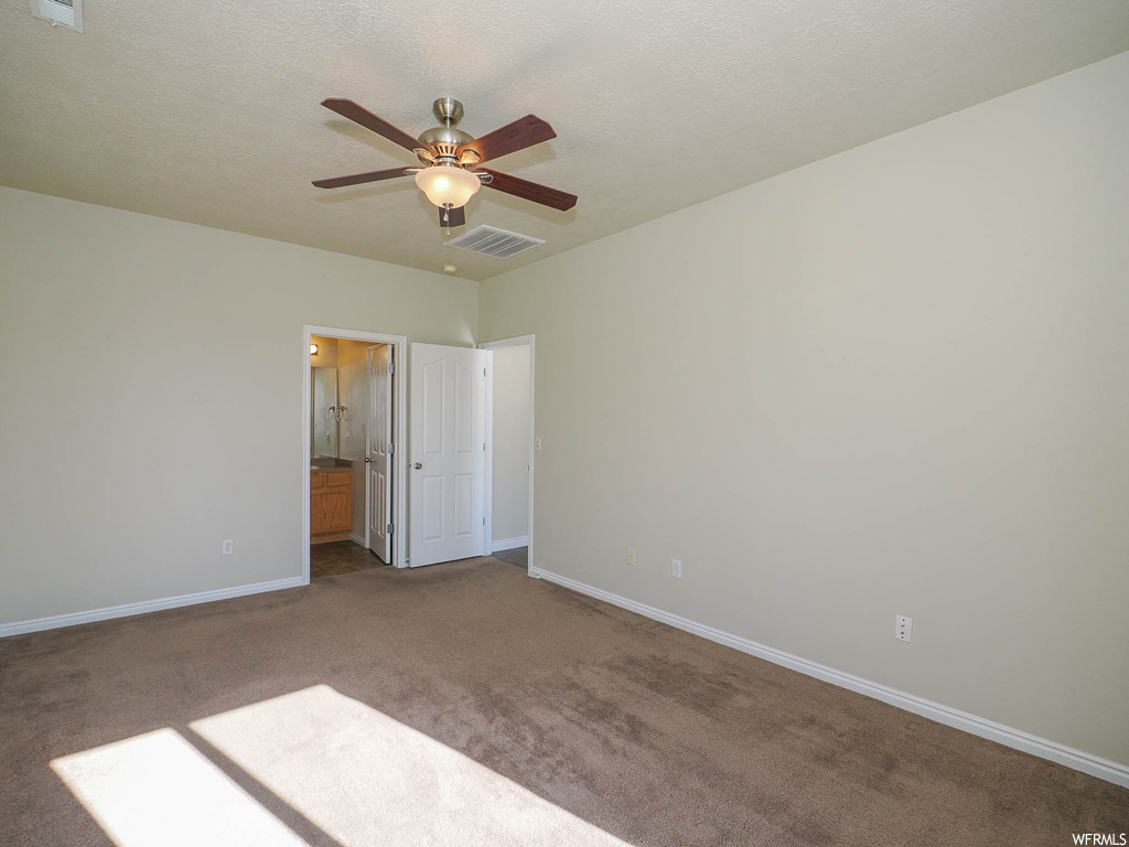 Spare room featuring ceiling fan, a textured ceiling, and dark carpet