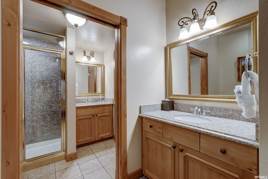 Bathroom with tile floors, a shower with shower door, and dual bowl vanity