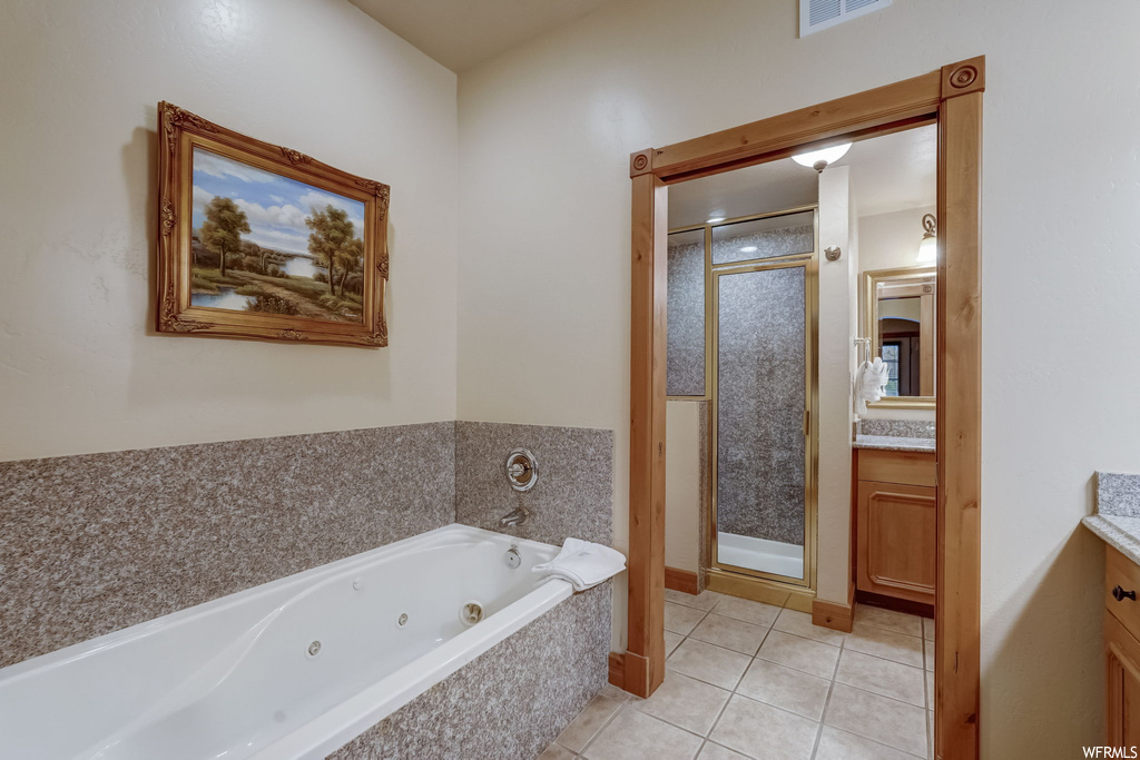 Bathroom with tile flooring, large vanity, and separate shower and tub