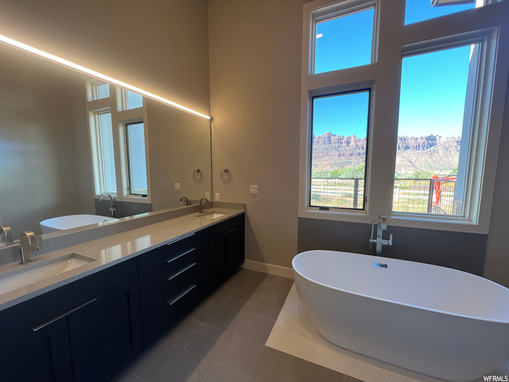 Bathroom with dual vanity, tile flooring, and a bathing tub