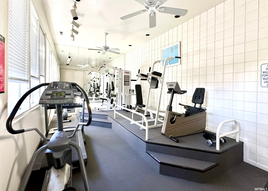Workout area featuring ceiling fan and tile walls