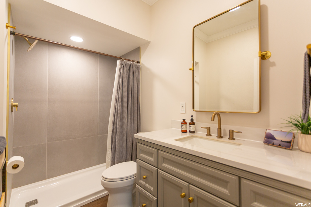 Bathroom featuring toilet, curtained shower, crown molding, and vanity