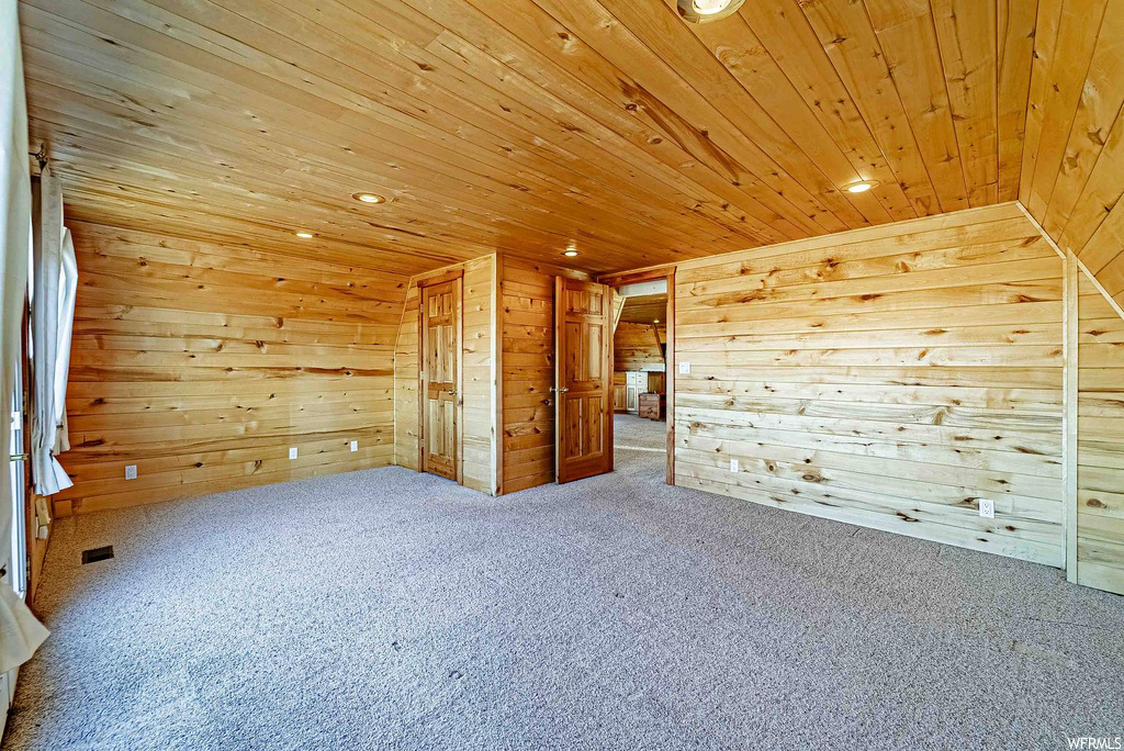 Additional living space with wooden walls, light colored carpet, and wooden ceiling
