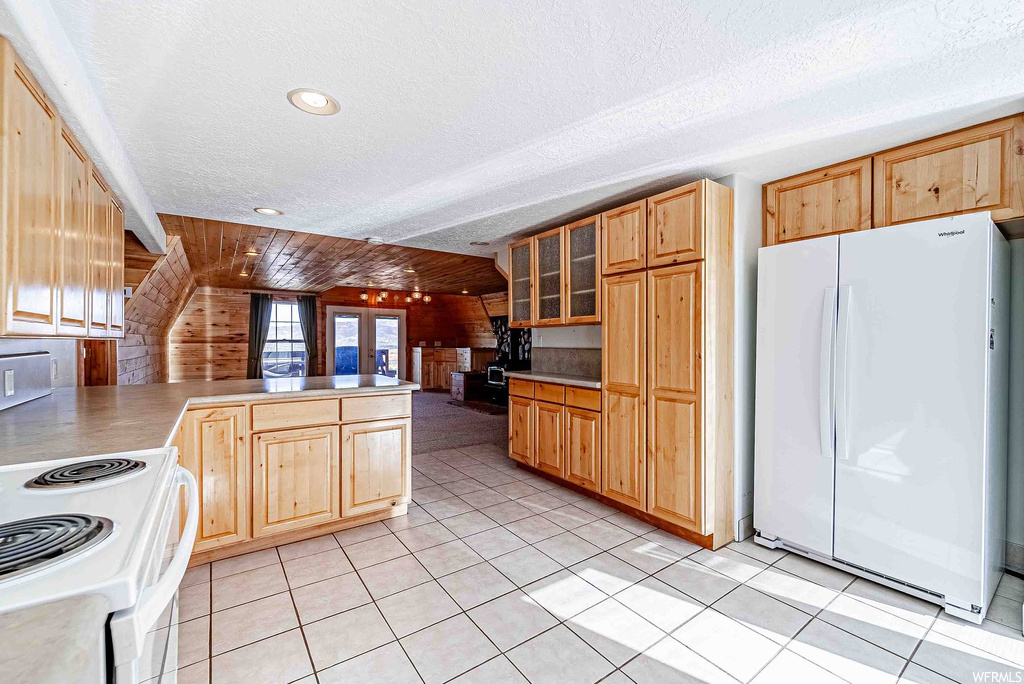 Kitchen with white appliances, wooden ceiling, light tile floors, and wooden walls