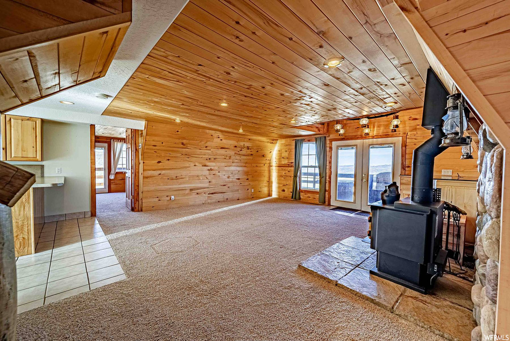 Unfurnished living room with plenty of natural light, a wood stove, and wood ceiling
