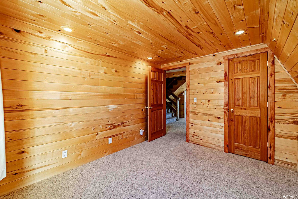 Interior space with light carpet, wooden walls, and wood ceiling