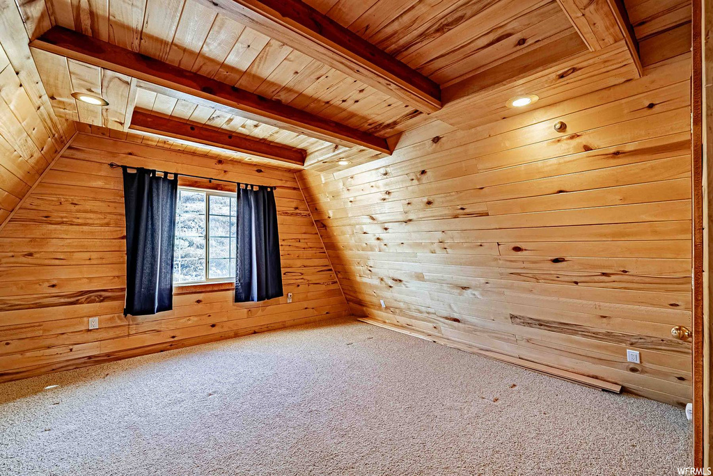 Additional living space featuring light carpet, lofted ceiling with beams, wooden walls, and wood ceiling