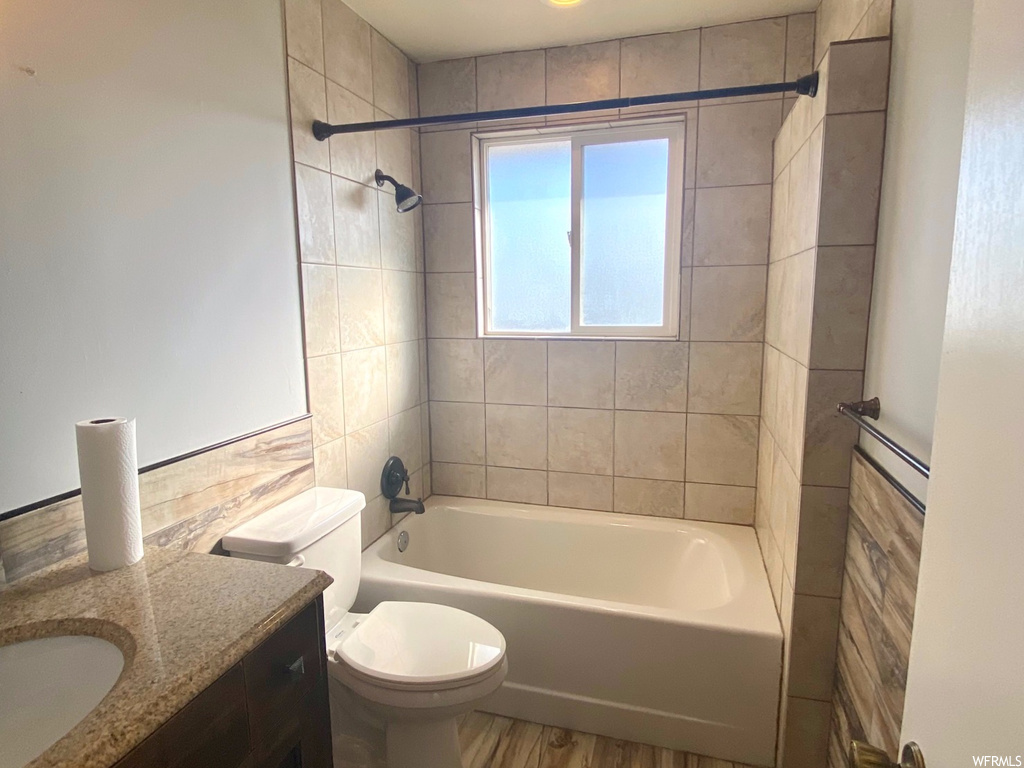 Full bathroom featuring toilet, hardwood / wood-style flooring, vanity, and tiled shower / bath