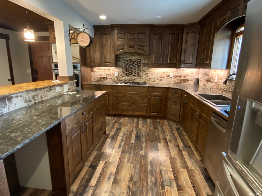 Kitchen featuring dark brown cabinetry, tasteful backsplash, dark stone countertops, and dark hardwood / wood-style floors