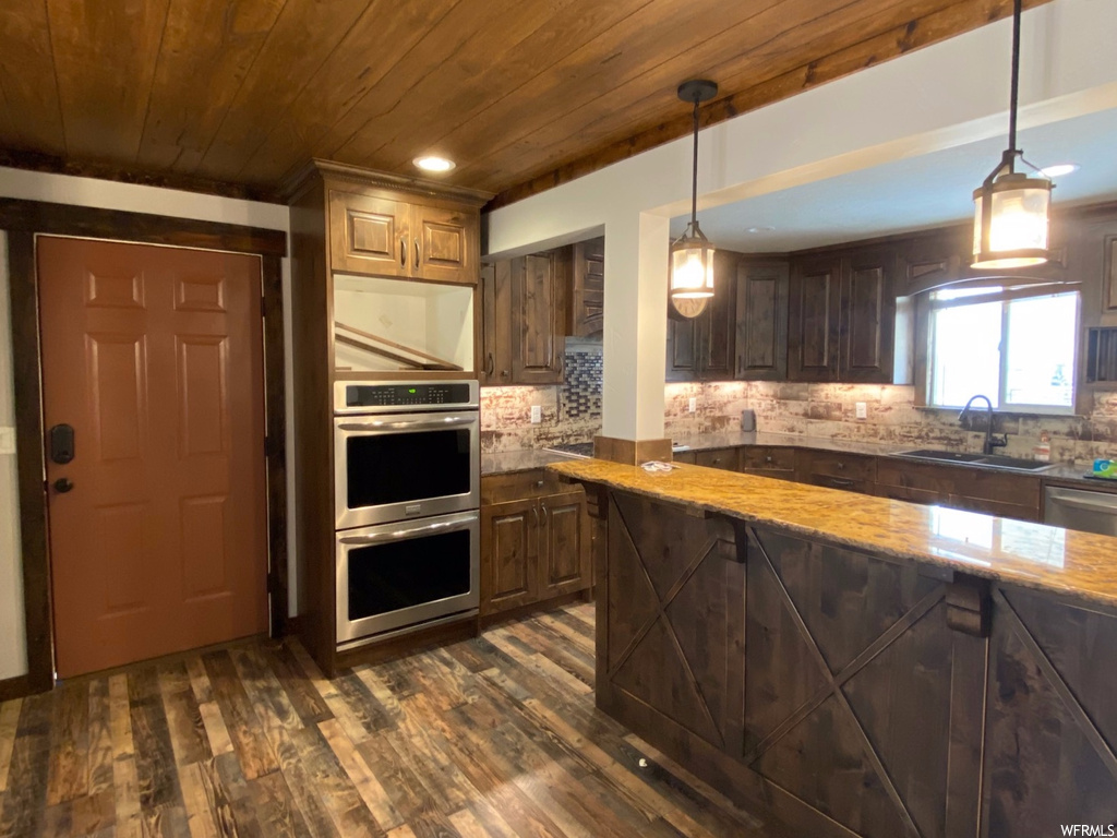 Kitchen with decorative light fixtures, dark hardwood / wood-style flooring, and backsplash