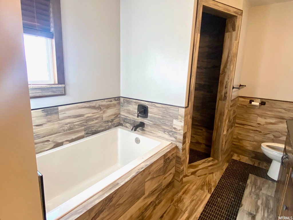 Full bathroom featuring vanity, tile walls, toilet, and independent shower and bath
