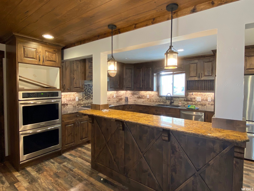 Kitchen featuring a center island, appliances with stainless steel finishes, dark hardwood / wood-style flooring, wooden ceiling, and pendant lighting