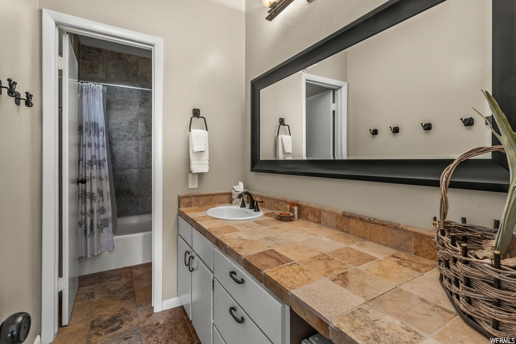 Bathroom with tile floors, vanity, and shower / bath combo with shower curtain