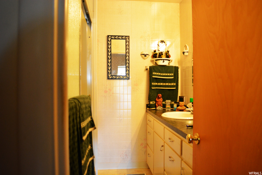 Bathroom featuring tile walls and vanity