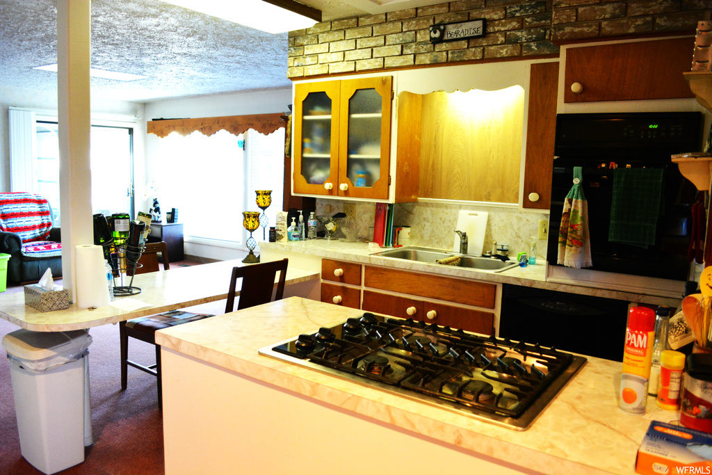 Kitchen with tasteful backsplash, sink, a textured ceiling, dark carpet, and black appliances