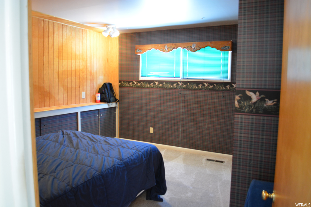 Carpeted bedroom with wood walls