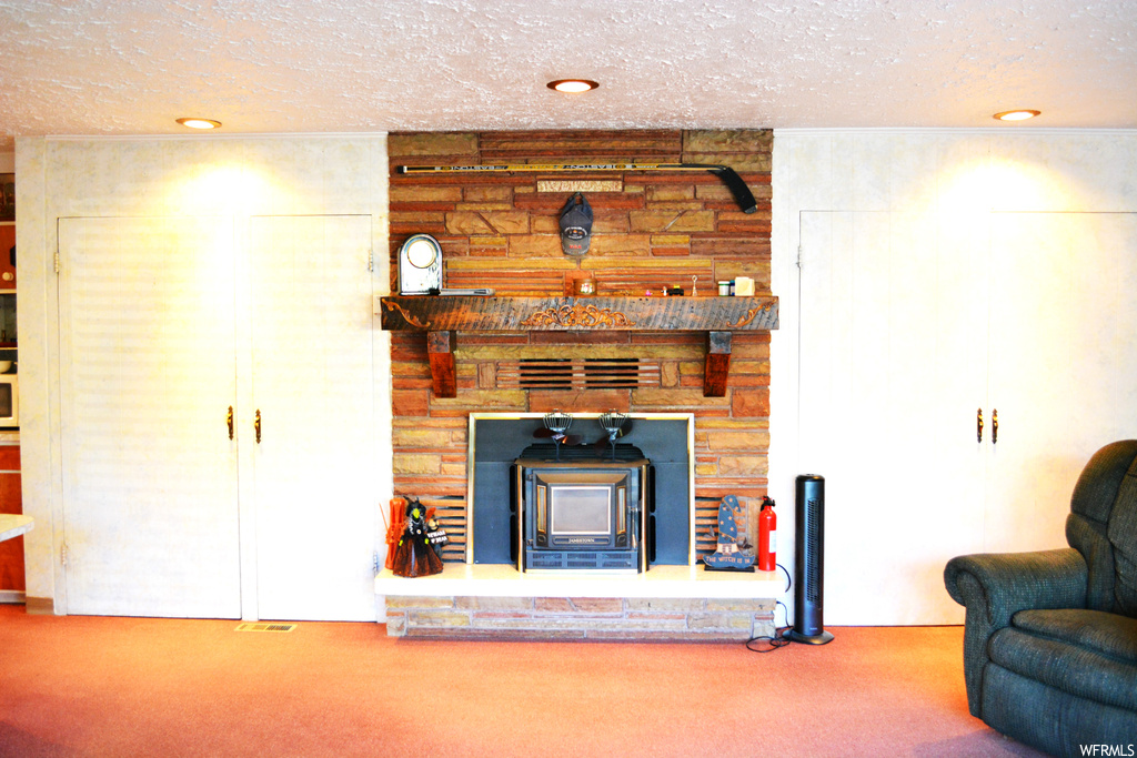 Unfurnished living room featuring carpet, a fireplace, and a textured ceiling